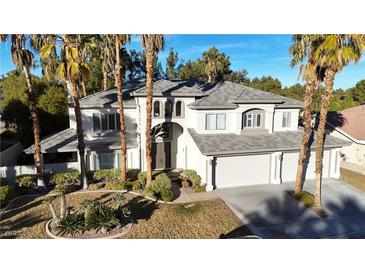 Two-story house with gray roof, three-car garage, and palm trees at 10008 Rolling Glen Ct, Las Vegas, NV 89117