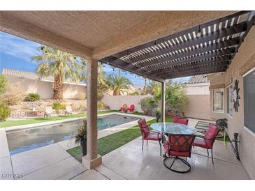 Relaxing backyard featuring a covered patio with seating, a sparkling pool, and well-maintained landscaping at 2144 Paganini Ave, Henderson, NV 89052