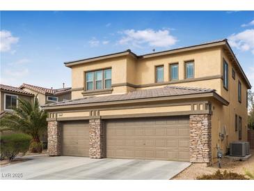 Two-story house with tan exterior, two-car garage, and stone accents at 1932 Barrow Glen Ct, North Las Vegas, NV 89084