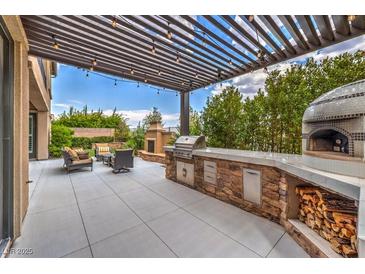 Outdoor kitchen with pizza oven, grill, and pergola at 3267 Royal Fortune Dr, Las Vegas, NV 89141