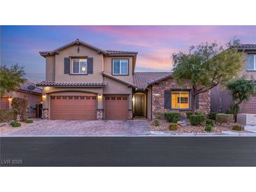 Two-story house with tan siding, brown garage doors, and stone accents at 7563 Saguaro Cactus Ave, Las Vegas, NV 89178