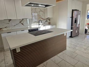 Modern kitchen with white cabinets, quartz countertops, and a stylish island at 116 W Victory Rd, Henderson, NV 89015