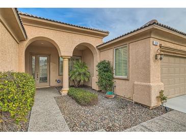 Inviting entryway with arched entry, mature shrubs, and a paved walkway at 5124 Pensier St, Las Vegas, NV 89135