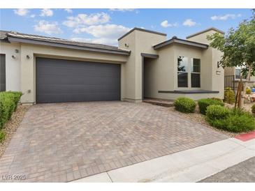 Modern home exterior with gray garage door and paved driveway at 9911 Spinel Pl, Las Vegas, NV 89143