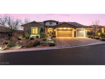 Beautiful brick home with landscaped yard and two-car garage at dusk at 12169 Castilla Rain Ave, Las Vegas, NV 89138