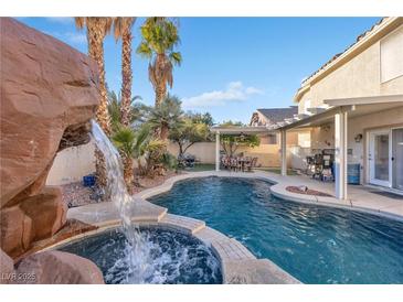 Inviting backyard oasis featuring a sparkling pool, waterfall, and covered patio at 8529 Copper Knoll Ave, Las Vegas, NV 89129