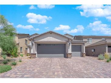 Two-story house with gray exterior, paver driveway, and landscaping at 1606 Dire Wolf Ave, North Las Vegas, NV 89084