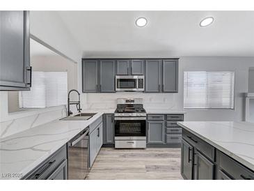 Modern kitchen with gray cabinets, white quartz countertops, and stainless steel appliances at 524 Blackbird Knoll Ct, North Las Vegas, NV 89084