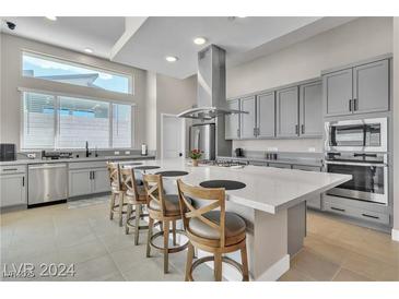 This kitchen offers grey cabinets, stainless appliances, an island with seating, and lots of natural light at 10301 Fairview Ridge Ct, Las Vegas, NV 89166