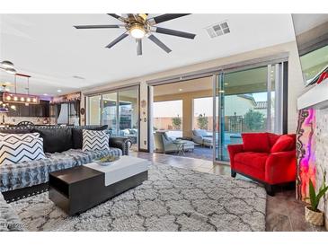 Spacious living room with a large sliding door, modern ceiling fan, stylish rug, and comfortable seating area at 10729 Beecher Park Ave, Las Vegas, NV 89166