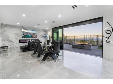 Modern dining room with a glass table, black chairs, marble accent wall and a stunning view at 1168 Spago Ln, Henderson, NV 89052