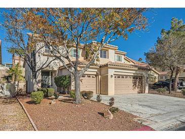 Two-story house with beige exterior, three-car garage, and landscaping at 1624 Ravanusa Dr, Henderson, NV 89052