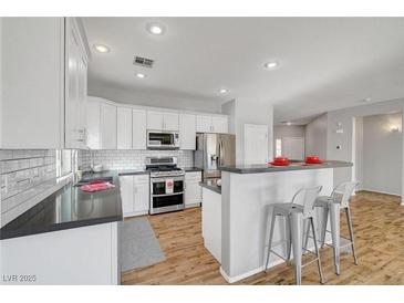A modern kitchen featuring white cabinets, stainless steel appliances, and a breakfast bar with seating at 5919 Pavilion Lakes Ave, Las Vegas, NV 89122