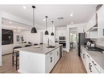 Modern kitchen with white cabinets, large island, and stainless steel appliances at 6545 Vanhoven Crest St, Las Vegas, NV 89166