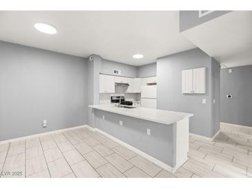 Modern kitchen with white cabinets, quartz countertops, and stainless steel appliances at 2251 Wigwam Pkwy # 211, Henderson, NV 89074