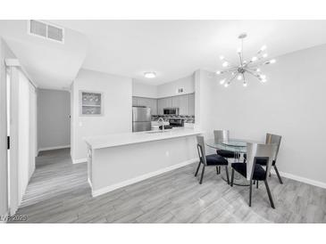 Modern kitchen with stainless steel appliances and breakfast bar flows into dining area at 2251 Wigwam Pkwy # 218, Henderson, NV 89074