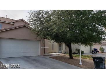 Beige house with a two-car garage and mature tree in front at 5987 Stone Hollow Ave, Las Vegas, NV 89156