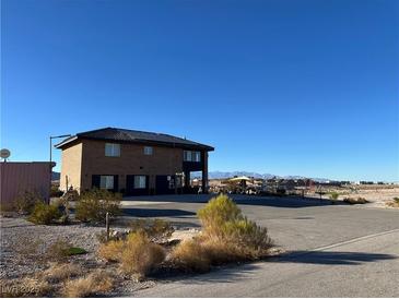 Two-story home showcasing its brickwork, dark trim, and solar panels, nestled in a desert landscape with views of distant mountains at 12745 Fairfield Ave, Henderson, NV 89044