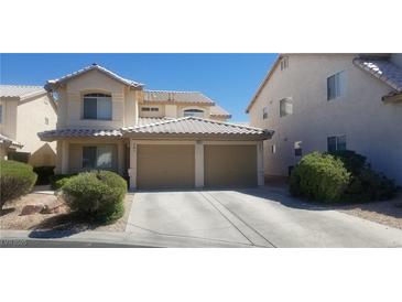 Two-story house with tan exterior, two-car garage, and landscaping at 7555 Glowing Ember Ct # 201, Las Vegas, NV 89130