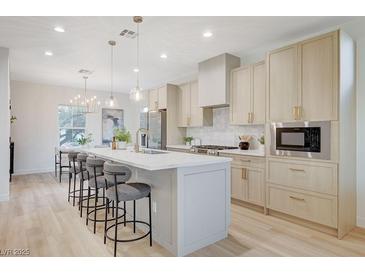 Modern kitchen with island, stainless steel appliances, and light wood cabinets at 2183 Sawtooth Mountain Dr, Henderson, NV 89044