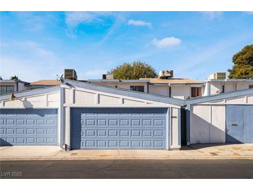 Front view of a townhouse with a two-car garage and blue doors at 4071 Village Sq, Las Vegas, NV 89121