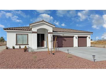 Single-story home with three-car garage, and landscaped front yard at 2560 Tahachapi Ave, Pahrump, NV 89048