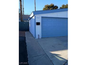 Attached garage with light blue roll-up door and driveway at 4031 Gold Coast Dr, Las Vegas, NV 89121