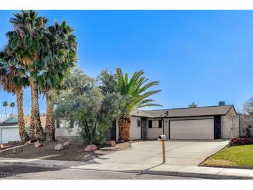 Single-story home with attached two-car garage, landscaping, and palm trees at 4457 Dennis Way, Las Vegas, NV 89121