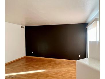 Bright living room featuring hardwood floors, neutral walls, and a large window for natural light at 698 S Racetrack Rd # 711, Henderson, NV 89015