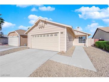 Beige house with a two-car garage and landscaped yard at 5892 Whispering Pine Ave, Las Vegas, NV 89142