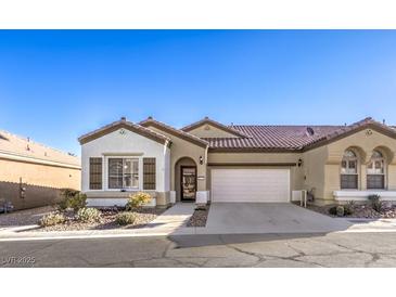 Tan two-story house with brown roof, attached garage, and landscaping at 2408 Sky Watcher St, Henderson, NV 89044