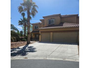 Two story tan home with a large two car garage and beautiful desert landscaping at 5805 Cabo San Lucas Ave, Las Vegas, NV 89131