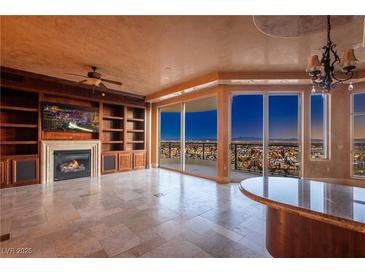 Luxury living room boasts built-in shelving, fireplace, and stunning city views at 9101 Alta Dr # 903, Las Vegas, NV 89145