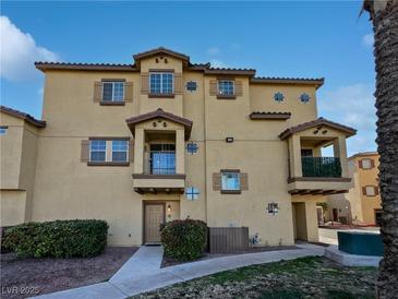 Tan three-story townhome with balcony and landscaping at 5960 Palmilla St # 3, North Las Vegas, NV 89031