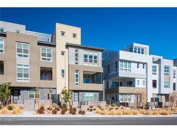 Contemporary townhomes featuring unique architectural details and desert landscaping under a clear blue sky at 11809 Stone Run Ave, Las Vegas, NV 89138