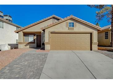 Single story home with tan exterior, paved driveway, and attached garage at 6560 Bush Clover Ln, Las Vegas, NV 89156