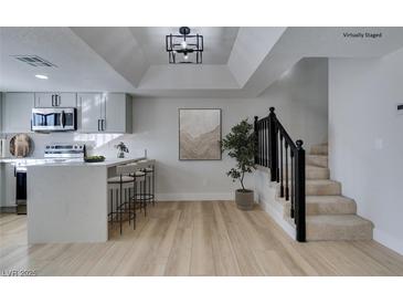 Modern kitchen with island, stainless steel appliances, and adjacent dining area at 3367 Vema Dr, Las Vegas, NV 89121