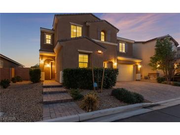 Two-story house with a landscaped front yard, brick walkway, and two-car garage at dusk at 8853 Sherborne Gate Ave, Las Vegas, NV 89148