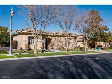 Single-story home with beige exterior, landscaping, and a large front yard at 9316 Provence Garden Ln, Las Vegas, NV 89145