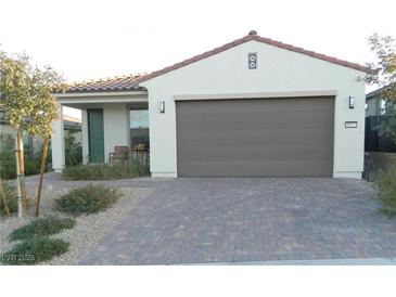 Single-story home featuring a brick driveway, a two-car garage and desert landscaping at 9577 Among Ln, Las Vegas, NV 89143