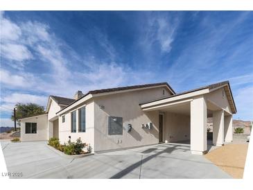 Tan house with carport and landscaping under a clear sky at 1409 Denver St, Boulder City, NV 89005