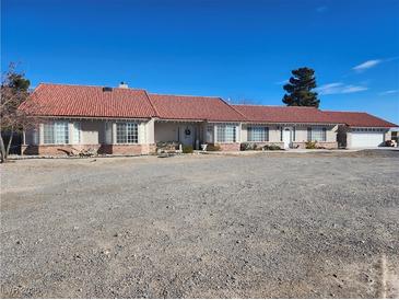 Single-story home with red tile roof and spacious gravel driveway at 2651 Homestead Rd, Pahrump, NV 89048