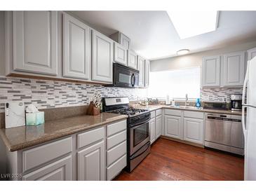 Modern kitchen with granite countertops, stainless steel appliances, and gray cabinets at 6575 Ellerhurst Dr, Las Vegas, NV 89103