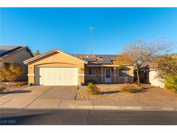 Tan one-story house with solar panels, white garage door, and landscaping at 1066 Bootspur Dr, Henderson, NV 89012