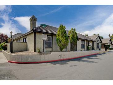 Tan colored exterior of house with brown accents, landscaped yard, and driveway at 3971 Foxboro Cir, Las Vegas, NV 89121