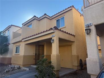 Tan two-story house with balcony, attached garage, and landscaping at 4043 Asante Cove St, Las Vegas, NV 89115