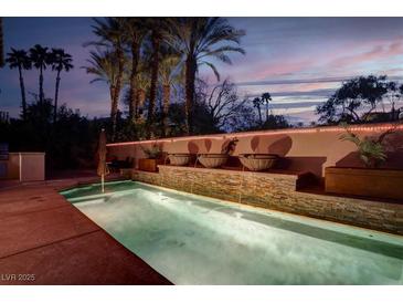 Inviting pool area featuring custom water feature wall and lush palm trees at 36 Avenida Fiori, Henderson, NV 89011