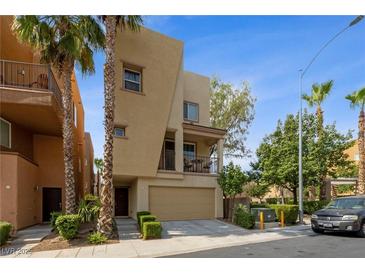 Tan two story home with a tan garage door, small balcony, and desert landscaping at 9331 Hilgard Ave, Las Vegas, NV 89178