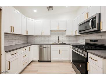 Modern kitchen with white cabinets, gray countertops, and stainless steel appliances at 3263 Gold Run St, North Las Vegas, NV 89032