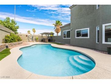 Beautiful pool with baja step, concrete surround, and outdoor kitchen for relaxing and entertaining at 6112 Browning Way, Las Vegas, NV 89130